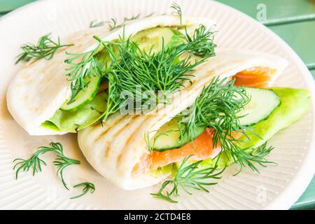 Pita-Sandwich mit geräuchertem Lachs, Gurke, Salat und gehacktem Dill darauf. Stockfoto