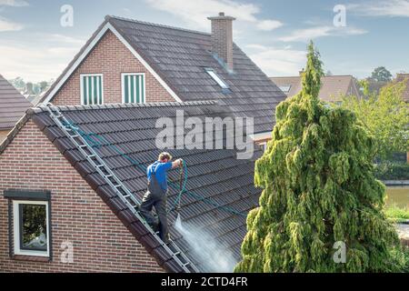 Reiniger mit Druckwascher am Dachhaus Reinigung Dachziegel Stockfoto