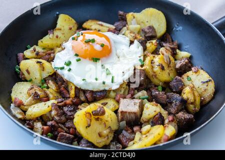 Tiroler Spezialität Grostl (Kartoffeln und Speck mit einem Spiegelei gekrönt). Stockfoto