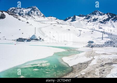 Verschneite Berglandschaft rund um die Bergstation Eisgrat im Stubaier Gletschergebiet in Tirol, Österreich, mit gefrorenem Bach. Stockfoto