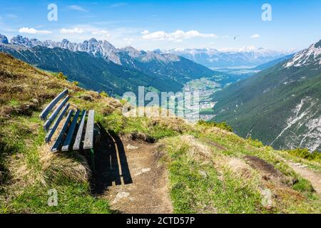 Bank auf einem Wanderweg im Elfermassiv in Tirol, Österreich, mit Stubaital im Hintergrund. Stockfoto