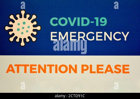 Ein Warnschild 'COVID-19 Notfall. Achtung bitte", in englischer Sprache geschrieben, rät, vorsichtig zu sein, um Coronavirus und die mögliche zweite Welle Stockfoto