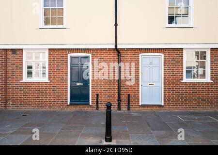 Zwei Eingangstüren, eine dunkelblau, eine hellblau, auf einer modernen Terrasse Stadthaus mit Backstein untere Fassade und glatt gerendert oben. Stockfoto