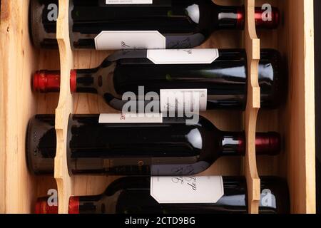 Flaschen Rotwein liegen flach in einer Holzkiste. Stockfoto
