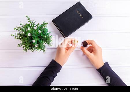 Junge Frau beten und Kommunion nehmen - der Wein und das Brot Symbole von Jesus Christus Blut und Körper mit der Heiligen Bibel. Ostern Passah und Lord Su Stockfoto