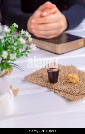 Junge Frau beten und Kommunion nehmen - der Wein und das Brot Symbole von Jesus Christus Blut und Körper mit der Heiligen Bibel. Ostern Passah und Lord Su Stockfoto