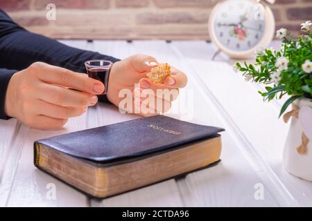 Junge Frau beten und Kommunion nehmen - der Wein und das Brot Symbole von Jesus Christus Blut und Körper mit der Heiligen Bibel. Ostern Passah und Lord Su Stockfoto