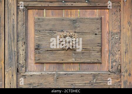Eine kleine Blume auf einer alten Holztür geschnitzt Stockfoto