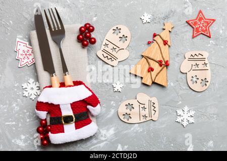 Blick von oben auf die Gabel und Messer mit Band auf Serviette auf Zement Hintergrund gebunden. Nahaufnahme von Weihnachtsschmuck und Tannenbaum. Happy Holiday conc Stockfoto