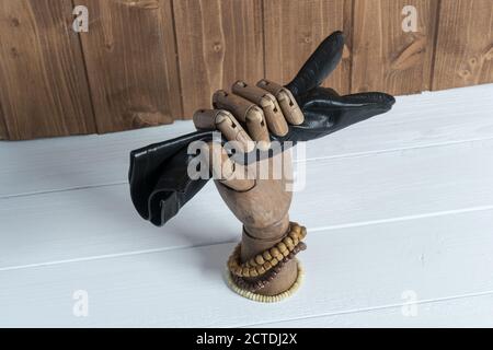 Ein Lederhandschuh, der von einer Holzhand auf einem gehalten wird Tabelle Stockfoto