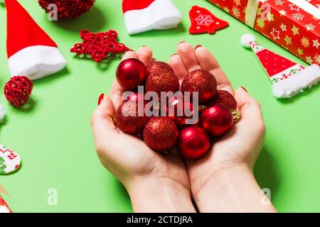 Blick von oben auf einen Haufen neues Jahr Kugeln in weibliche Hände auf grünem Hintergrund aus festliche Dekorationen. Weihnachten Konzept. Stockfoto