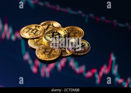 Nahaufnahme von goldenen Bitcoin-Münzen auf einem abwärts handelnden grafischen Hintergrund. Stockfoto