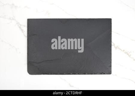 Leere schwarze Schieferplatte auf weißem Marmorhintergrund Stockfoto