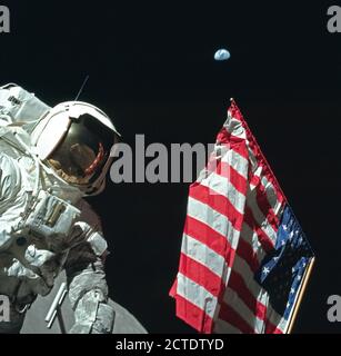 Astronaut Harrison Schmitt stellt auf der Mondoberfläche neben eine amerikanische Flagge während der Apollo 17. (Mond Oberfläche unten am Bild zu sehen) Stockfoto