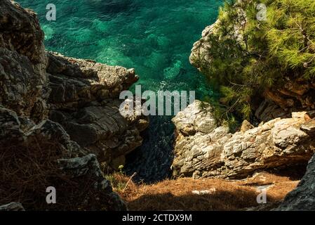 Felsige Klippen mit reinem sauberen grünen und blauen Wasser der Adria in der Nähe von Sveti Stefan Insel. Unheimliche Aussicht von oben. Stockfoto