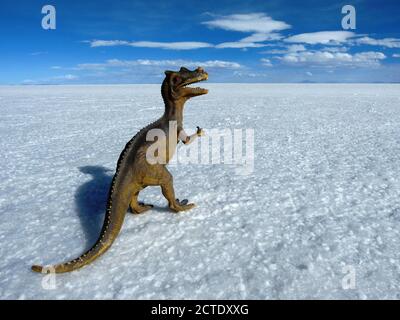 Spielzeug Dinosaurier in der weißen Wüste. Tyrannosaurus in Salinen von Uyuni, Bolivien, Altiplano. Perspektivischer Hintergrund. Salar de Uyuni. Blauer Himmel. Horizont Stockfoto