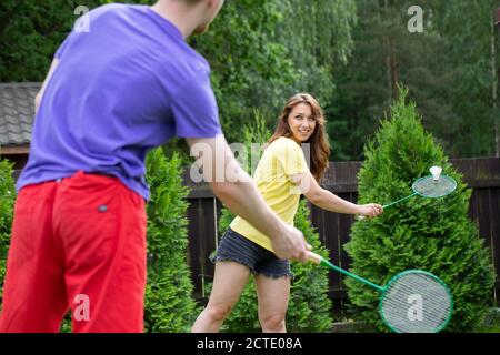 Junge Sport-Paar spielt Badminton im Freien im Park. Freizeit, Sommerkonzept Stockfoto