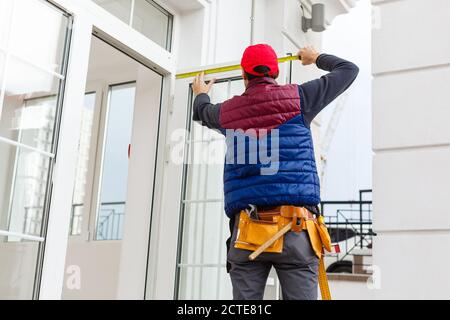 Ein Arbeiter installiert Panels beige Abstellgleis auf der Fassade des Hauses Stockfoto