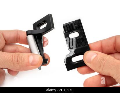 Zwei Hände, die eine zerbrochene Schlagplatte aus einer Crashbar einer Wohn- oder Geschäftsfeuerschutztür halten. Durch Diebe / Einbrecher mit Brechstange beschädigt. Stockfoto