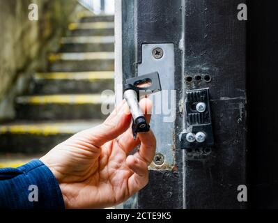 Hand hält gebrochene Schlagplatte von einer Wohn- oder Gewerbeimmobildtür. Beschädigung von Türrahmen und Schlagplatte durch Diebe / Einbrecher usin Stockfoto