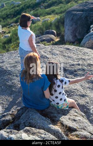 Familie in der Natur, drei Generationen von Frauen beobachten die Zukunft in der Horizontalen, nachdem sie den Berg erreicht haben. Erfahrungen teilen. Ich freue mich auf die Zukunft Stockfoto