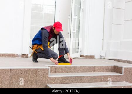 Ein Arbeiter installiert Panels beige Abstellgleis auf der Fassade des Hauses Stockfoto