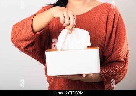 Junge Frau Grippe sie mit Hand, die weißes Gesichtstuch aus einer weißen Box für sauberes Taschentuch herausziehen, Studio auf weißem Hintergrund isoliert Stockfoto