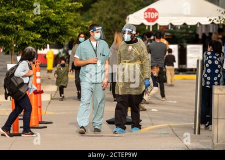 Toronto, Kanada - 22. September 2020. Medizinisches Personal in PSA-Kleidung wird vor dem Women's College Hospital Covid-19 Assessment Center gesehen, während die Leute im Hintergrund darauf warten, getestet zu werden. Quelle: EXImages/Alamy Live News Stockfoto