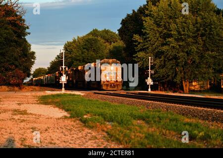 Maple Park, Illinois, USA. Ein Güterzug der Union Pacific Railroad fährt in Richtung der untergehenden Sonne, während er durch Maple Park, Illinois, fährt. Stockfoto