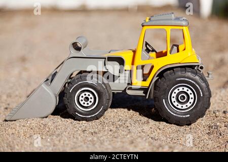 Gelber Plastikspielzeug-Traktor im Sandkasten Stockfoto