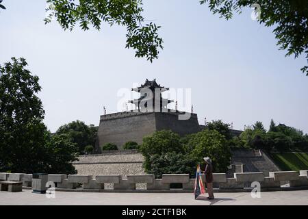 Ein alter Mann ist bereit, einen Drachen unter der alten Stadtmauer und dem Turm zu fliegen. Stockfoto