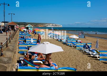 Sandown Strandpromenade Isle of Wight Windbreaks Liegestühle Sonnenschirme Liegestühle Am Strand an einem sonnigen hellen Tag Strandgänger Stockfoto