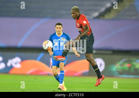 Der kamerunische Fußballspieler John Mary von Shenzhen F.C., rechts, übergibt den Ball während des vierten Spieles von 2020 Chinese Super League (CSL) gegen die Spieler Stockfoto