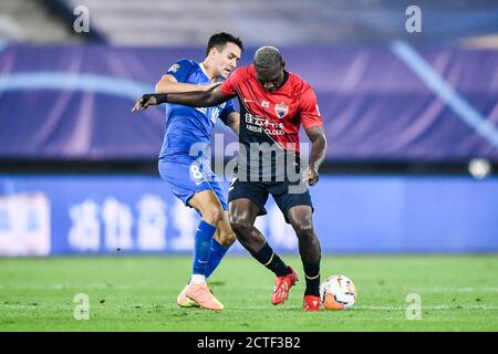 Der kamerunische Fußballspieler John Mary von Shenzhen F.C., rechts, schützt den Ball vor dem in England geborenen taiwanesischen Fußballspieler Tim Chow von Henan Jianye Stockfoto