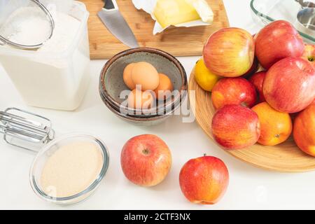 Apfelkuchen backen. Äpfel, Eier, Zucker, Butter, Mehl und einige Zutaten stehen auf einem Küchentisch ganz nah Stockfoto