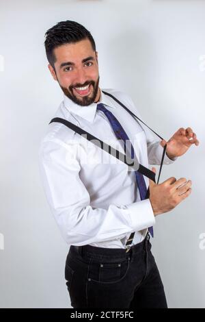 Hübscher junger Geschäftsmann zieht seine Hosenträger, scherzte und täuscht sich herum. Attraktive stilvolle bärtige Mann in formeller Kleidung Spaß haben. Mittlere Aufnahme. W Stockfoto