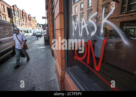 Das sich wandelnde Gesicht der Hauptstraße. Ein Mann, der ein Gesicht trägt, geht an Graffitti vorbei, mit dem Slogan "Mask On", der ein leeres Schaufenster in der High Street in Worcester bedeckt, etwa sechs Monate nach dem Abend des 23. März, als Premierminister Boris Johnson landesweite Beschränkungen ankündigte. Stockfoto