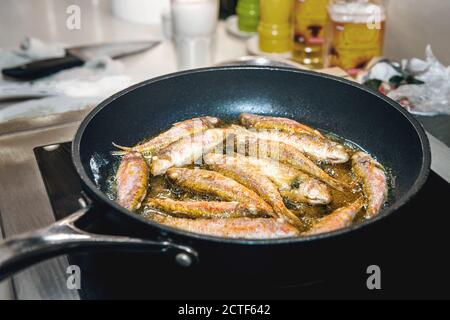 Kleine Barabul-Fische und Stöcker werden darin gebraten Öl in einer Pfanne auf einem Induktionsherd Stockfoto