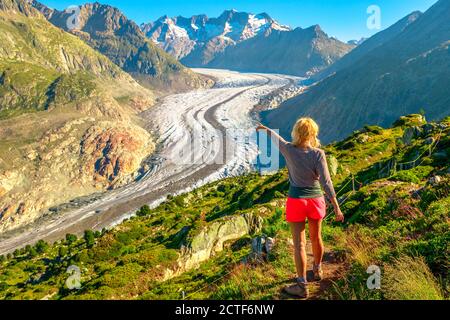 Aletschgletscher vom Aussichtspunkt Moosfluh im Sommer, Kanton Wallis, Schweiz, Europa. Wanderfrau zeigte auf den Alpengletscher. Im Freien Stockfoto