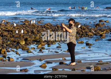 Eine Frau, die zum Schutz vor dem Coronavirus eine Gesichtsmaske trägt, macht am 22. September 2020 ein Foto am Strand in Malibu, Kalifornien. (Foto von Ronen Tivony/Sipa USA) *** Bitte benutzen Sie das Credit from Credit Field *** Credit: SIPA USA/Alamy Live News Stockfoto