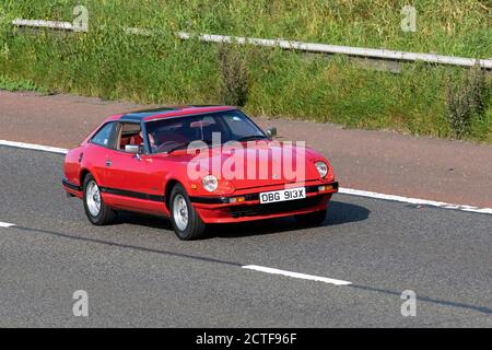 1982 80s Red Datsun 280 ZX Targa Auto; Vehicular Traffic Moving Vehicles, Autos, die Fahrzeuge auf britischen Straßen fahren, japanische Oldtimer, Autofahren auf dem Autobahnnetz M6. Stockfoto