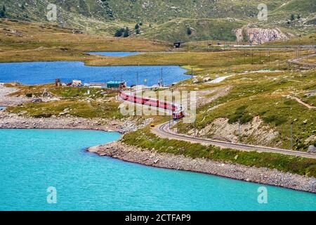 BERNINA Express-Zug am Weissen See in Ospizio Bernina, Oberengadin, Graubünden, Graubünden, Schweiz. Stockfoto
