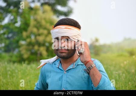 TIKAMGARH, MADHYA PRADESH, INDIEN - 15. SEPTEMBER 2020: Indischer Landwirt, der auf dem Sesamfeld ein Mobiltelefon benutzt. Stockfoto