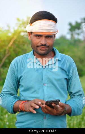 TIKAMGARH, MADHYA PRADESH, INDIEN - 15. SEPTEMBER 2020: Indischer Landwirt, der auf dem Sesamfeld ein Mobiltelefon benutzt. Stockfoto