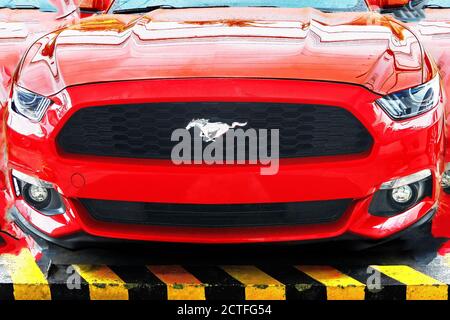 Isolierte Ansicht eines roten Ford Mustang Sportwagen, fotografiert von vorne niedrigen Winkel, retuschiert zu einer Collage, mit prominenten Pferd Symbol Stockfoto