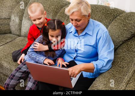 Großmutter mit Enkelkindern mit Laptop zu Hause Stockfoto
