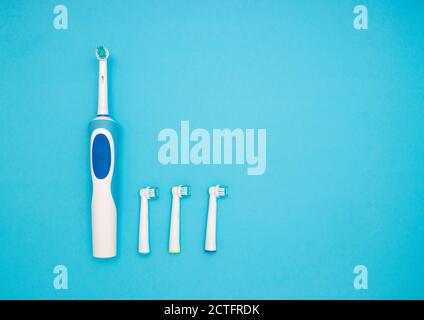 Mundhygiene. Elektrische Zahnbürste und Ersatzbürsten auf blauem Hintergrund. Der Blick von oben. Stockfoto