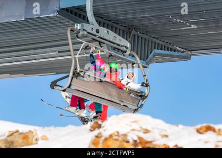 Gruppe Freunde Skifahrer und Snowboarder Mann und zwei Frauen Ski Lift auf blauem Himmel Hintergrund Stockfoto