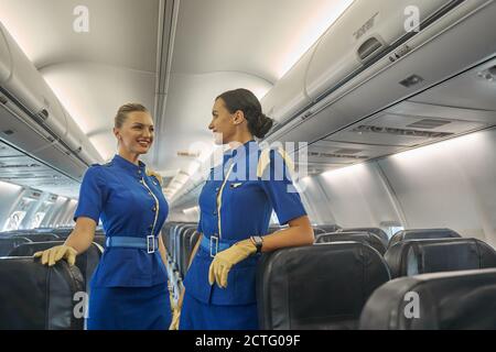 Zwei weibliche Kabinenbesatzungsmitglieder warten auf die Passagiere Stockfoto