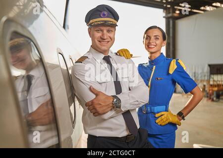 Glückliche Arbeiter der Fluggesellschaft stehen in einem Hangar Stockfoto